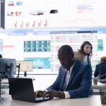 General director examining statistics big data on computer in a control room, makes a briefing report. Business manager studying sales numbers to adapt within market conditions.